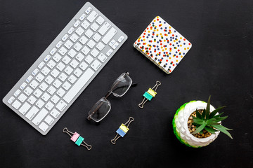 Obraz premium Work desk of manager. Computer keyboard, glasses, stationery, plant on black background top view space for text