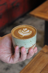 Latte coffee mug with hand in a coffee shop