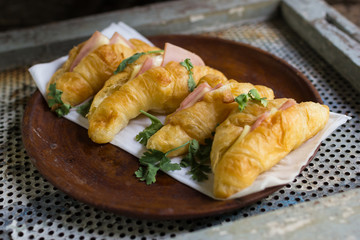 Croissant cheese in wooden dish placed on a rusty grill