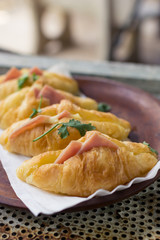 Croissant cheese in wooden dish placed on a rusty grill