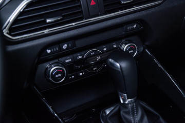 Fototapeta na wymiar Сlose-up of the car black interior: dashboard, adjustment of the blower, air conditioner, player, accelerator handle and other buttons.