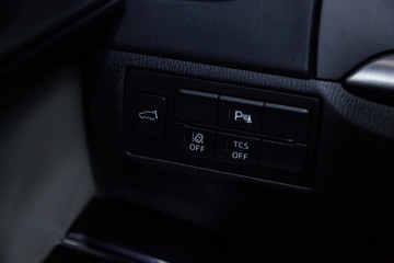 Fototapeta premium Сlose-up of the car black interior: trunk release buttons, parking systems and other buttons.