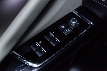 Сlose-up of the car  black interior:  the side door buttons: window adjustment buttons, door lock and other buttons.