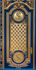 Ornate golden and blue door with fleur de lis pattern at the entrance of Les Invalides in Paris, France, burial site for many of France's war heroes, housing the tomb of the emperor Napoleon Bonaparte