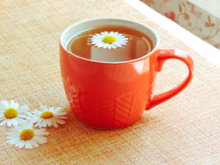 Cup of herbal tea with chamomile flowers. Healthy natural chamomile herbal.Herbal tea on a white wooden background. Cup of tea anti-inflammatory, antimicrobial herbal tea with fresh chamomile flowers.