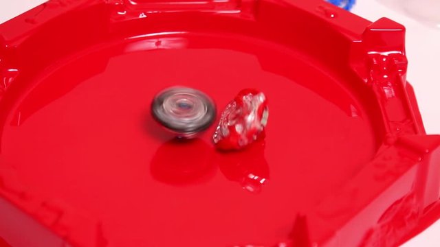 Popular Modern Children Game Beyblade Burst Fast spinning on red arena. Gyroscope, spinner Japanese toy