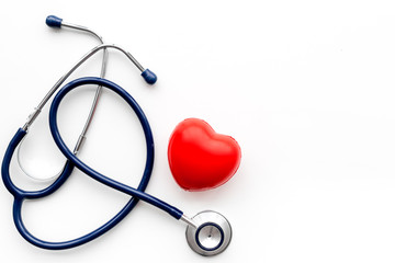 Heart health, health care concept. Stethoscope near rubber heart on white background top view copy space