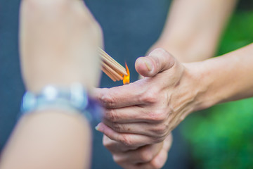 Close up hands lighting the incense sticks for made Brahma image worship