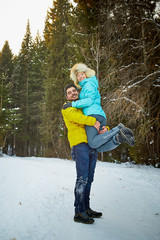 Happy loving couple in snowy winter forest. Ordinary Russian girl and handsome turkish man having fun and hug
