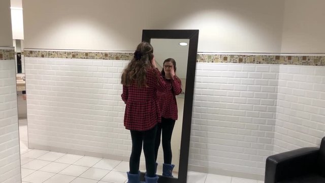 Tween girl looking at outfit in the mirror
