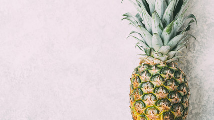Ripe pineapple on grey textured background.