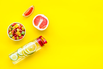 Diet rich in fruits. Slimming diet. Fruit salad near fruit lemon and cucumber water on yellow background top view copy space