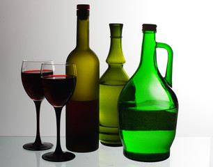 Two glasses of wine and wine bottles on a light background.