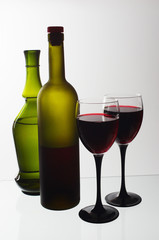 Two glasses of wine and wine bottles on a light background.