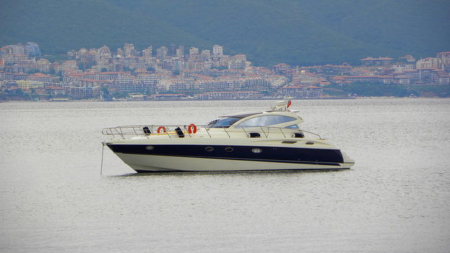Panorama. Seascape, complete calm, white-blue yacht at anchor, coastline with buildings resort town.