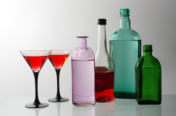 Two glasses of wine and wine bottles on a light background.