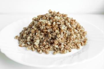 Buckwheat. Boiled buckwheat grains on a white plate. Concept food background.