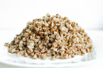 Buckwheat. Boiled buckwheat grains on a white plate. Concept food background.
