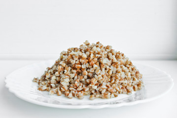 Buckwheat. Boiled buckwheat grains on a white plate. Concept food background.
