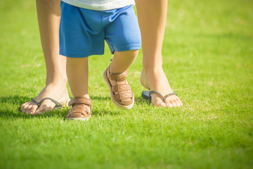 First baby steps. Closeup of babies feet walking with mothers help