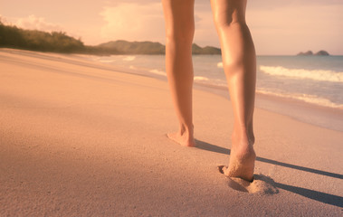 Naklejka premium Young woman walking down a beautiful white sand beach. 