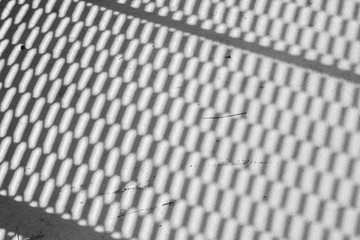 light and shadow of wire mesh on brick floor - monochrome