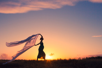 silhouette of young  pregnant woman at sunset