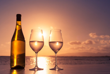 two glasses of wine on a beach sunset background 