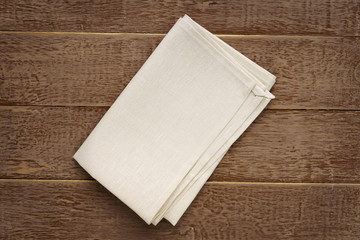 top view of cloth napkins of beige, color on rustic brown wooden table.