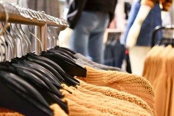 knit yellow sweaters on hangers hanging on a rack in a clothing store