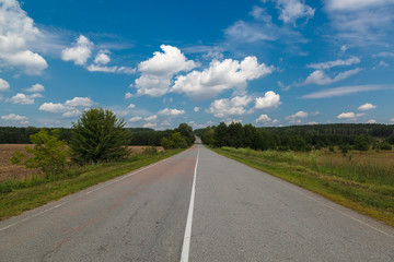 Fototapeta na wymiar Asphalt road on a background of blue sky with clouds