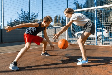 Streetball basketball game with two players, teenagers girl and boy with ball, outdoor city...