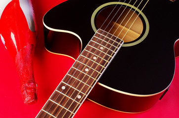 Acoustic guitar and bottle on red.