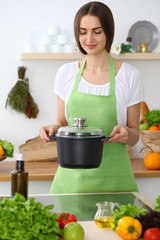 Beautiful Hispanic woman cooking soup in kitchen. Healthy meal and householding concepts