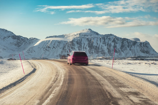 Red SUV Car Driving On Rural Road With Mountain In Winter