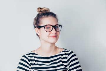 Smiling brunette woman in eyeglasses posing with and looking at the camera over white background