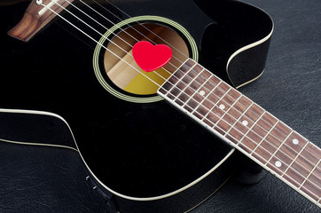 Fototapeta na wymiar Acoustic guitar and red heart-shaped plectrum.