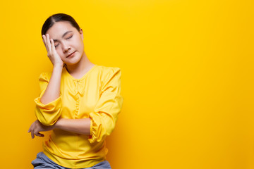 Woman has headache isolated over yellow background