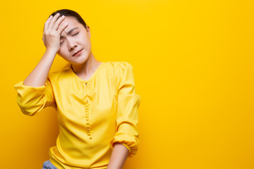 Woman has headache isolated over yellow background