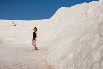 Natural travertine pools and terraces in Pamukkale. Cotton castle in southwestern Turkey, girl standing in natural pool. A woman in the pool of thermal springs at World Heritage Hierapolis Pamukkale