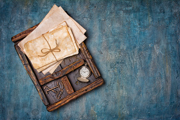 Old yellowed bunch of letters with retro keys and pocket watch in vintage wooden box