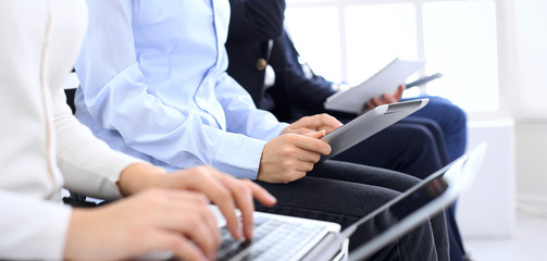 Group of business people sitting in office waiting for job interview, close-up. Hands of woman working on laptop. Conference or training concepts