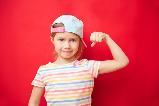 Attractive little girl shows the biceps on a red background. Feel so powerful. Girls rules concept. Upbringing advices for girls. Strong and powerful