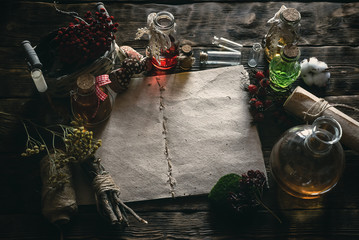 Ancient recipe scroll book and various dry herbs on a table of witch doctor. Herbal medicine essential oil on a table. Witchcraft background with copy space. - obrazy, fototapety, plakaty
