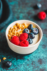 Vegetarian breakfast, a bowl with organic granola, fresh raspberries and blueberries and coconut yoghurt.