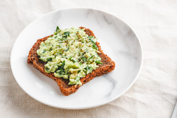 Avocado sandwich with rye bread on a plate. The concept of healthy balanced food.