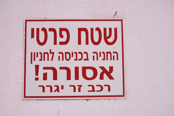 Signboard in Hebrew warning about private area and prohibition of parking. "Private area, parking at the entrance prohibited. The vehicle will be evacuated". 