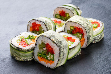 Sushi roll with vegetables on black background. Vegetarian dish.