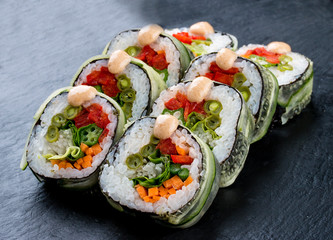 Sushi roll with vegetables on black background. Vegetarian dish.