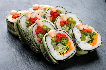 Sushi roll with vegetables on black background. Vegetarian dish.